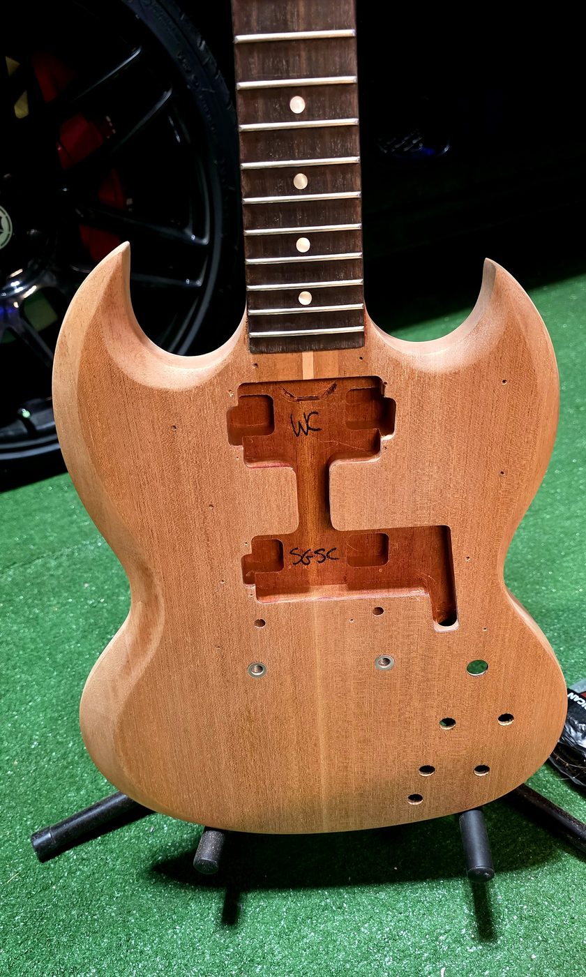SG-style guitar body stripped to raw mahogany during a full restoration