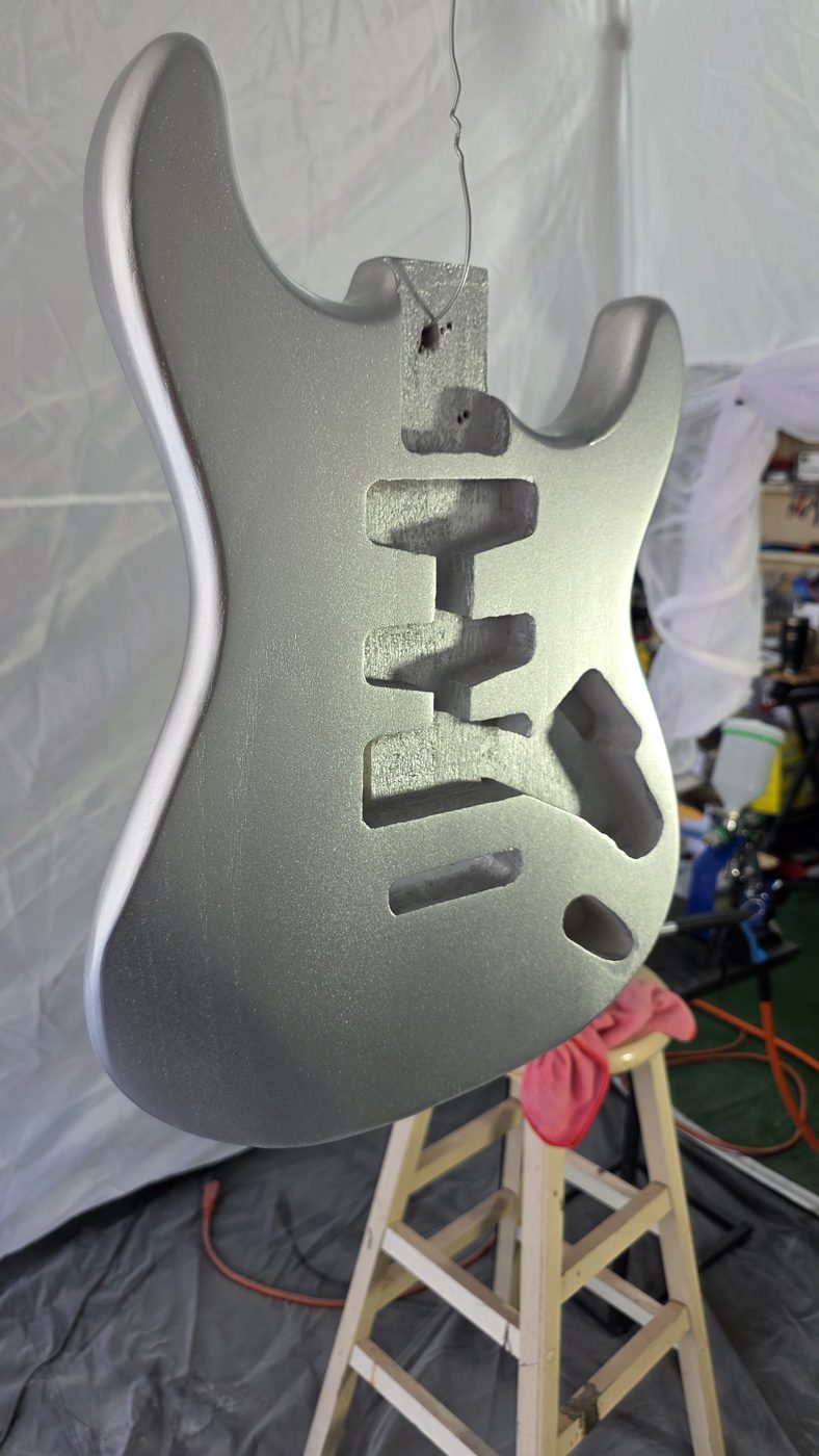 Guitar body mid-finish showing three-tiered nitrocellulose lacquer application